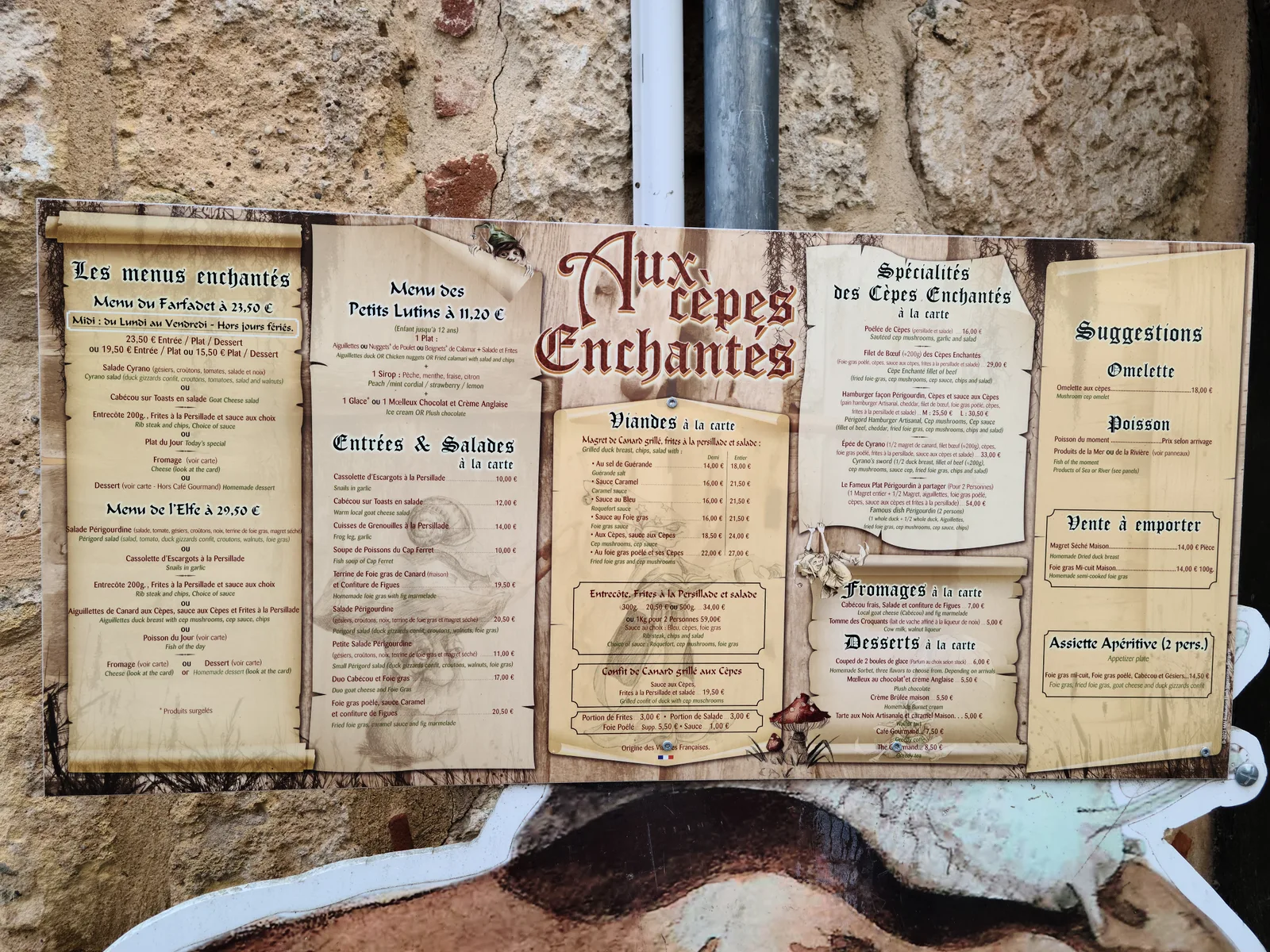 Elaborate outdoor menu board for Aux Crêpes Enchantées restaurant mounted on a stone wall in Bergerac's old town, showing menus and specialties in French