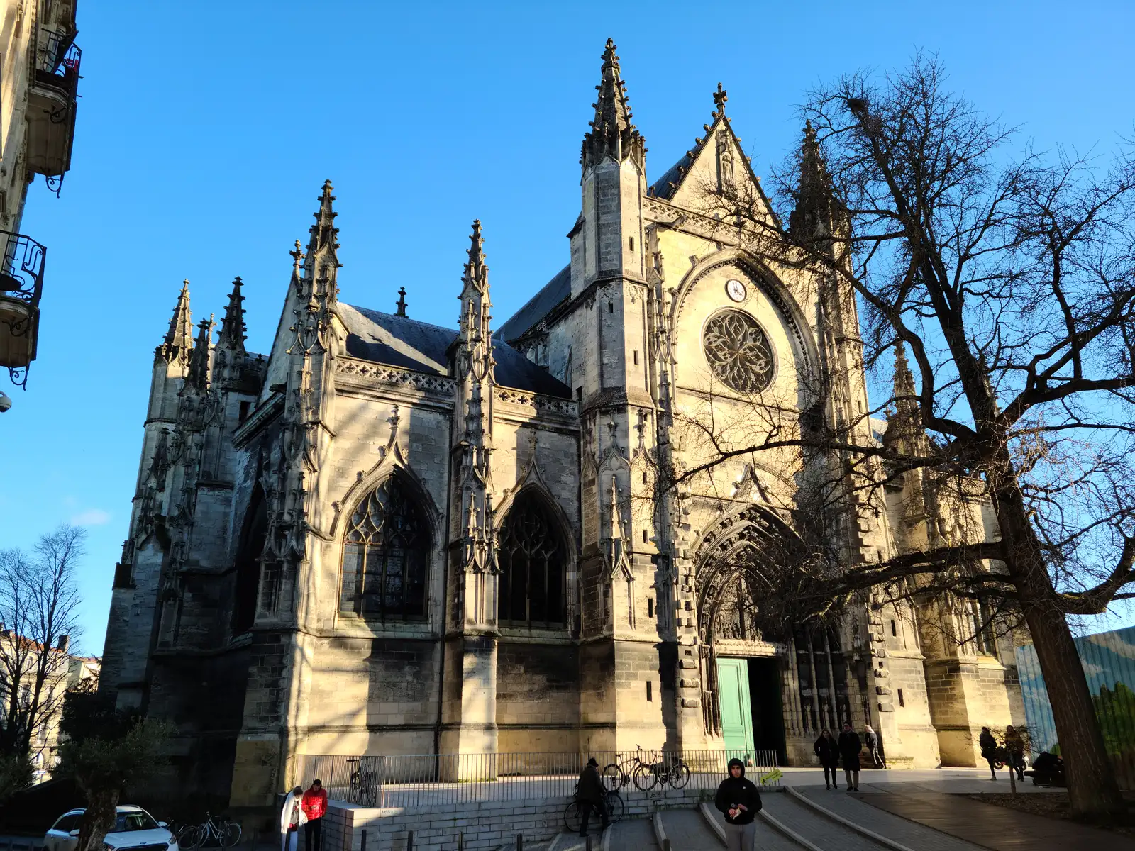 Gothic Basilique Saint-Michel with rose window, soaring spires, and flying buttresses against a deep blue winter sky in Bordeaux