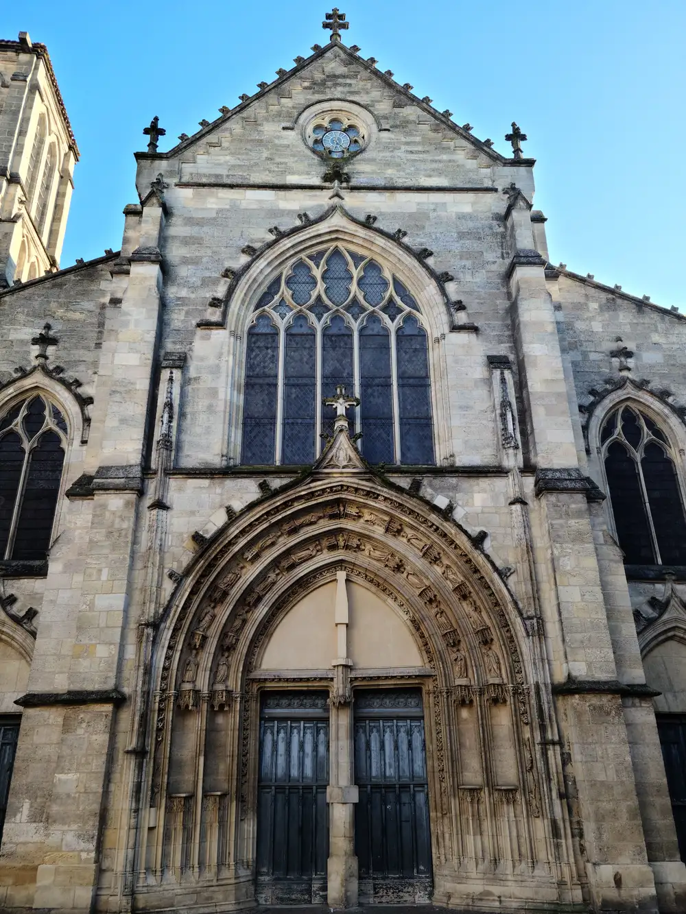 Upward view of the Gothic facade of Église Saint-Pierre with pointed arch portal and tracery window in Bordeaux