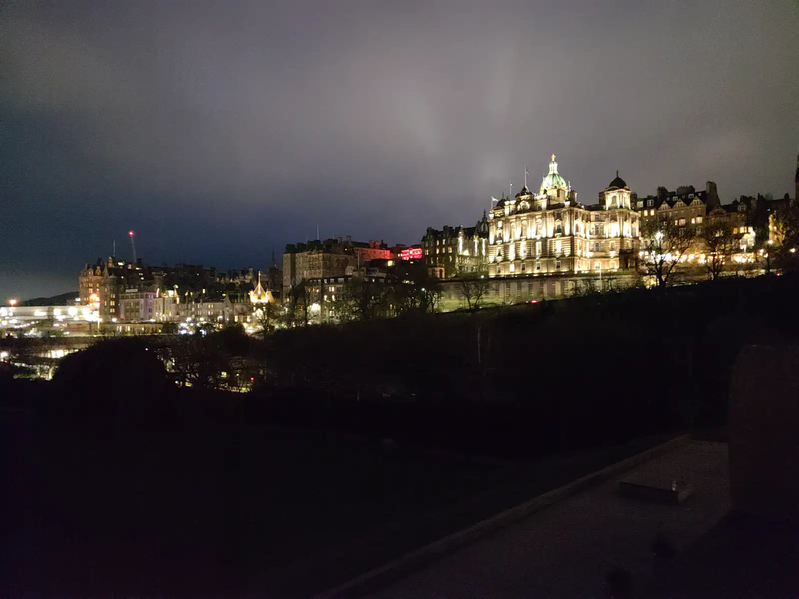 Floodlit Bank of Scotland headquarters with illuminated green dome rising above Edinburgh Old Town rooftops at night