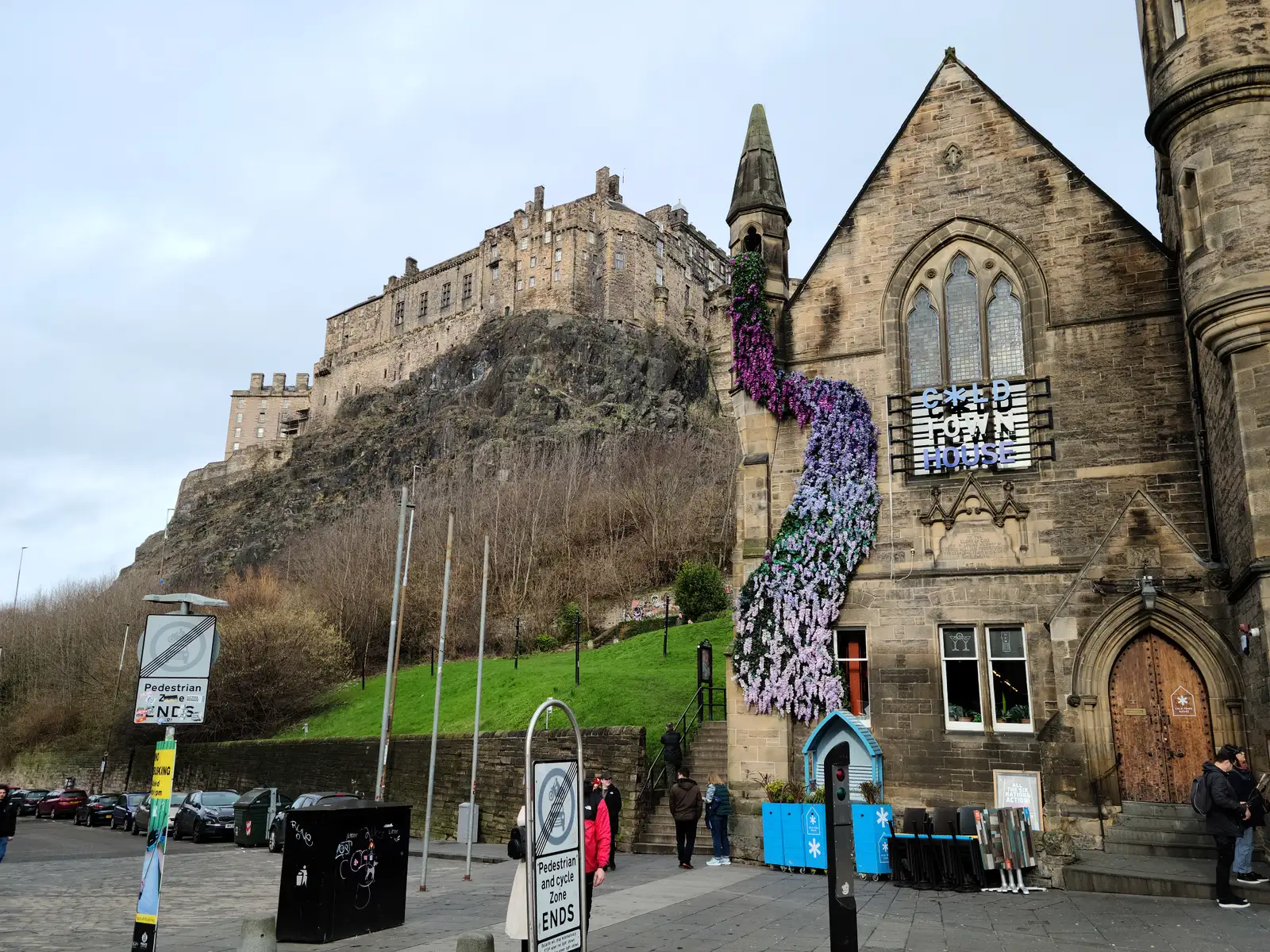 Cold Town House with cascading purple and lilac floral display beneath Edinburgh Castle on its volcanic crag at Grassmarket