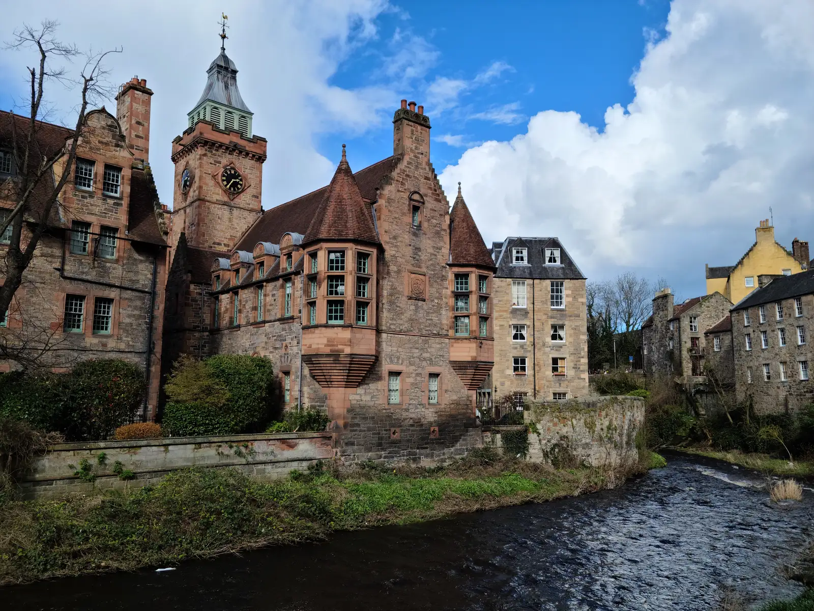 Well Court's red sandstone clock tower and turreted tenements rising above the Water of Leith in Edinburgh's Dean Village