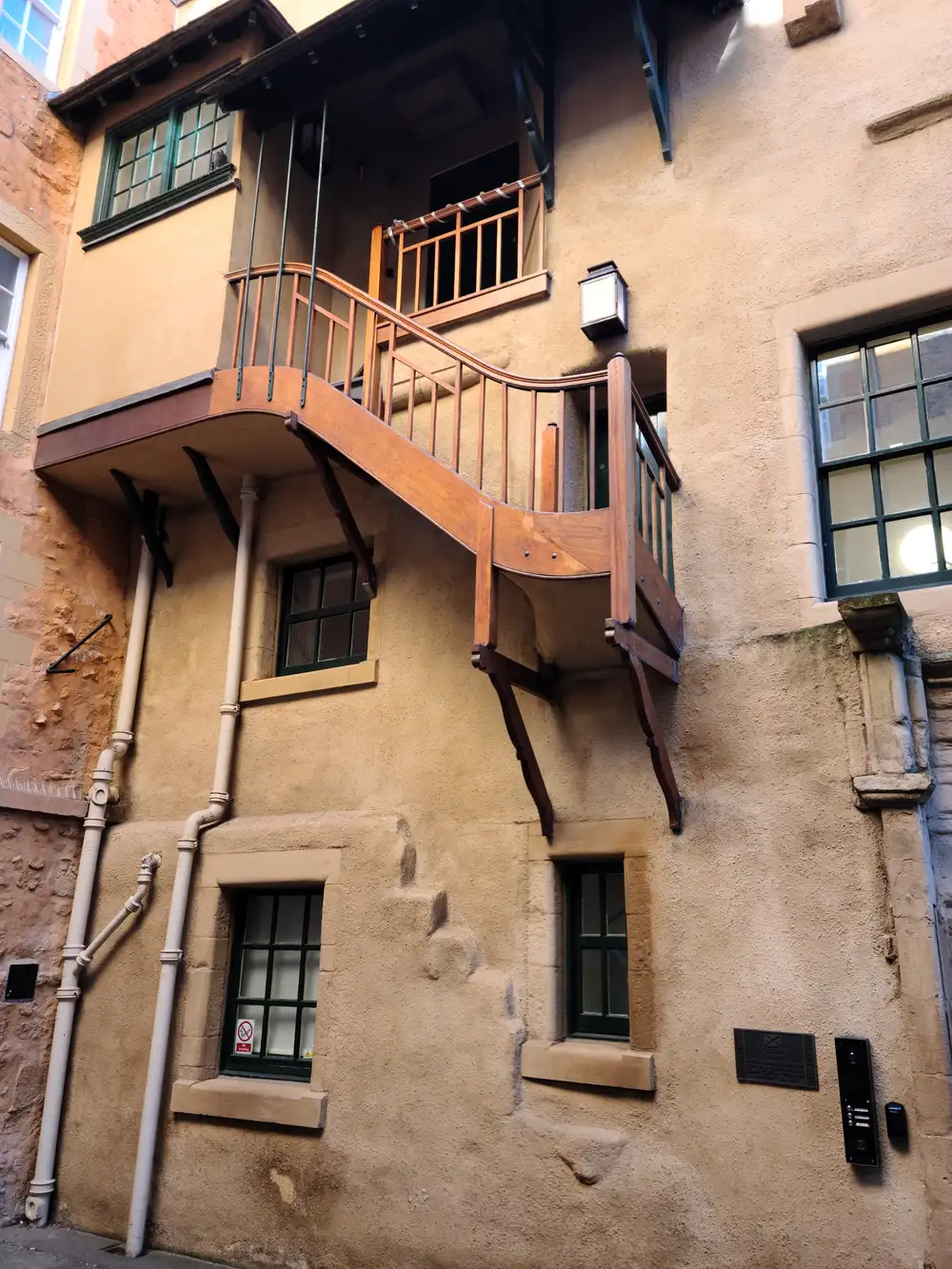 Curved wooden external staircase and balcony on a sandstone tenement in an Edinburgh Old Town close off the Royal Mile