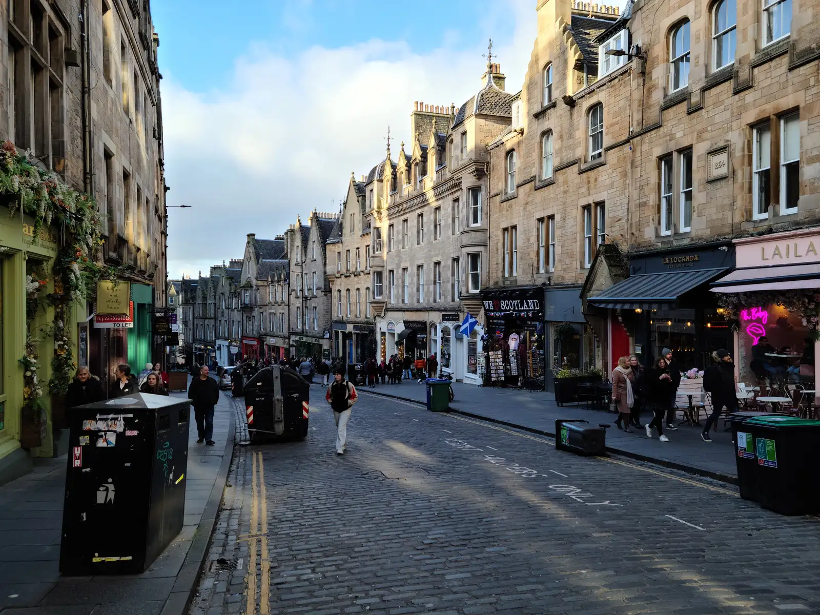 Curving cobbled Cockburn Street in Edinburgh Old Town with sandstone tenements, independent shops and pedestrians in winter light