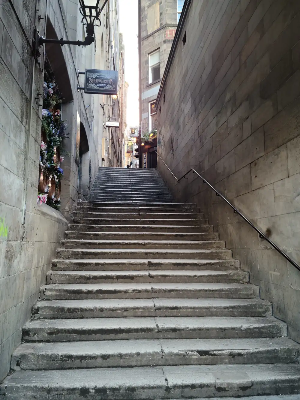 Steep stone staircase rising through Fleshmarket Close in Edinburgh Old Town with the Brewhemia hanging sign overhead