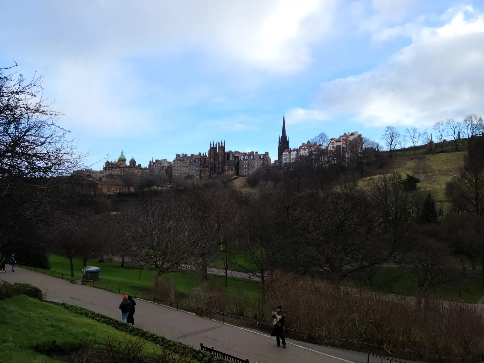 Edinburgh Old Town skyline with Tolbooth Kirk spire and tenements rising above Princes Street Gardens under blue winter sky