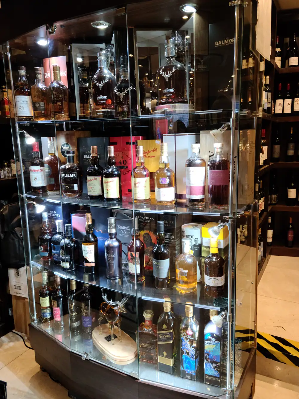 Illuminated glass cabinet of rare single malt Scotch whiskies including Dalmore 25, Balvenie and Johnnie Walker Blue in an Edinburgh shop