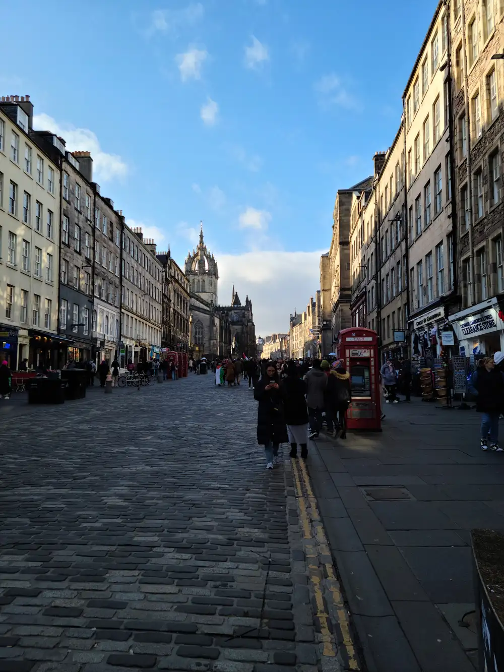Cobbled Royal Mile in Edinburgh leading towards St Giles' Cathedral crown spire with red phone box and winter crowds