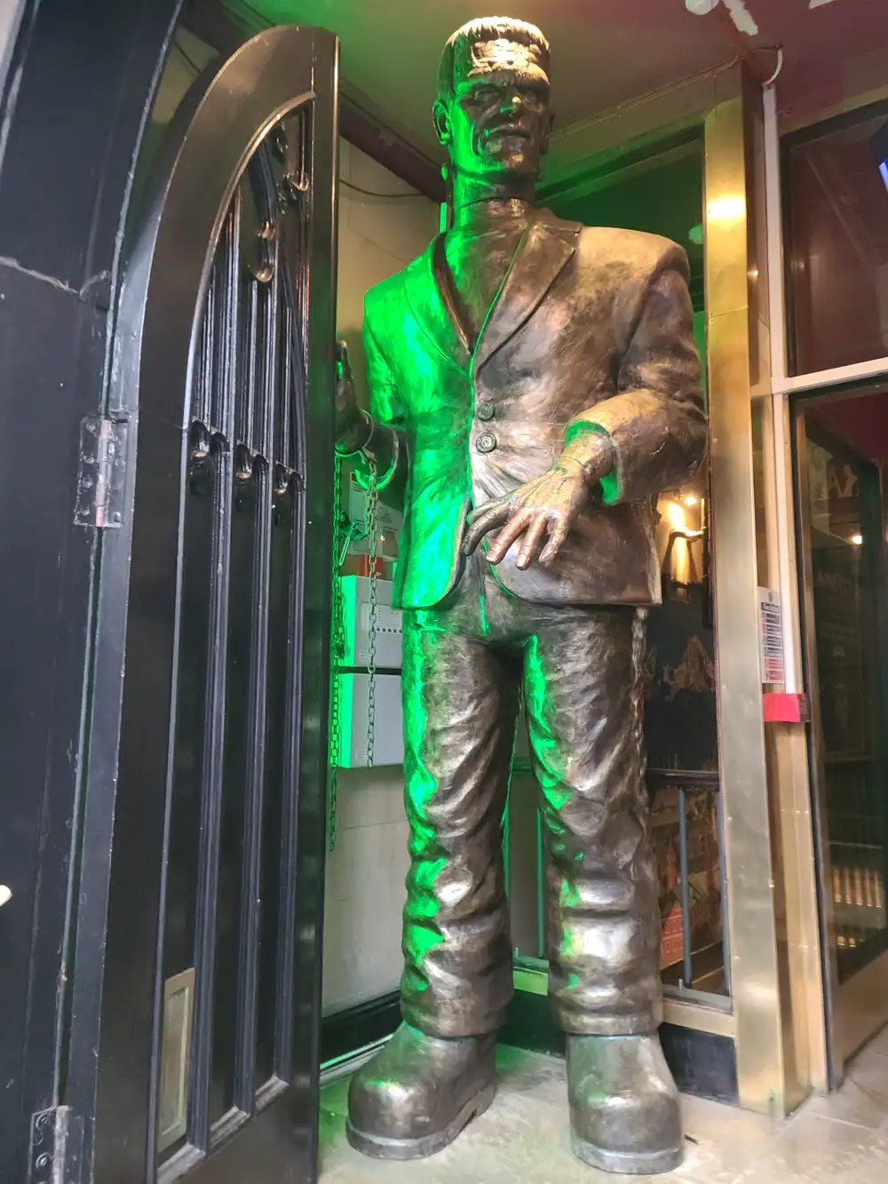 Towering bronze Frankenstein's monster statue lit with green light at the entrance to the Frankenstein pub on George IV Bridge in Edinburgh