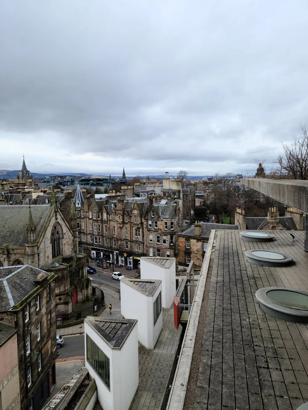 View from the National Museum of Scotland rooftop terrace across Edinburgh Old Town spires and tenements with oval skylights