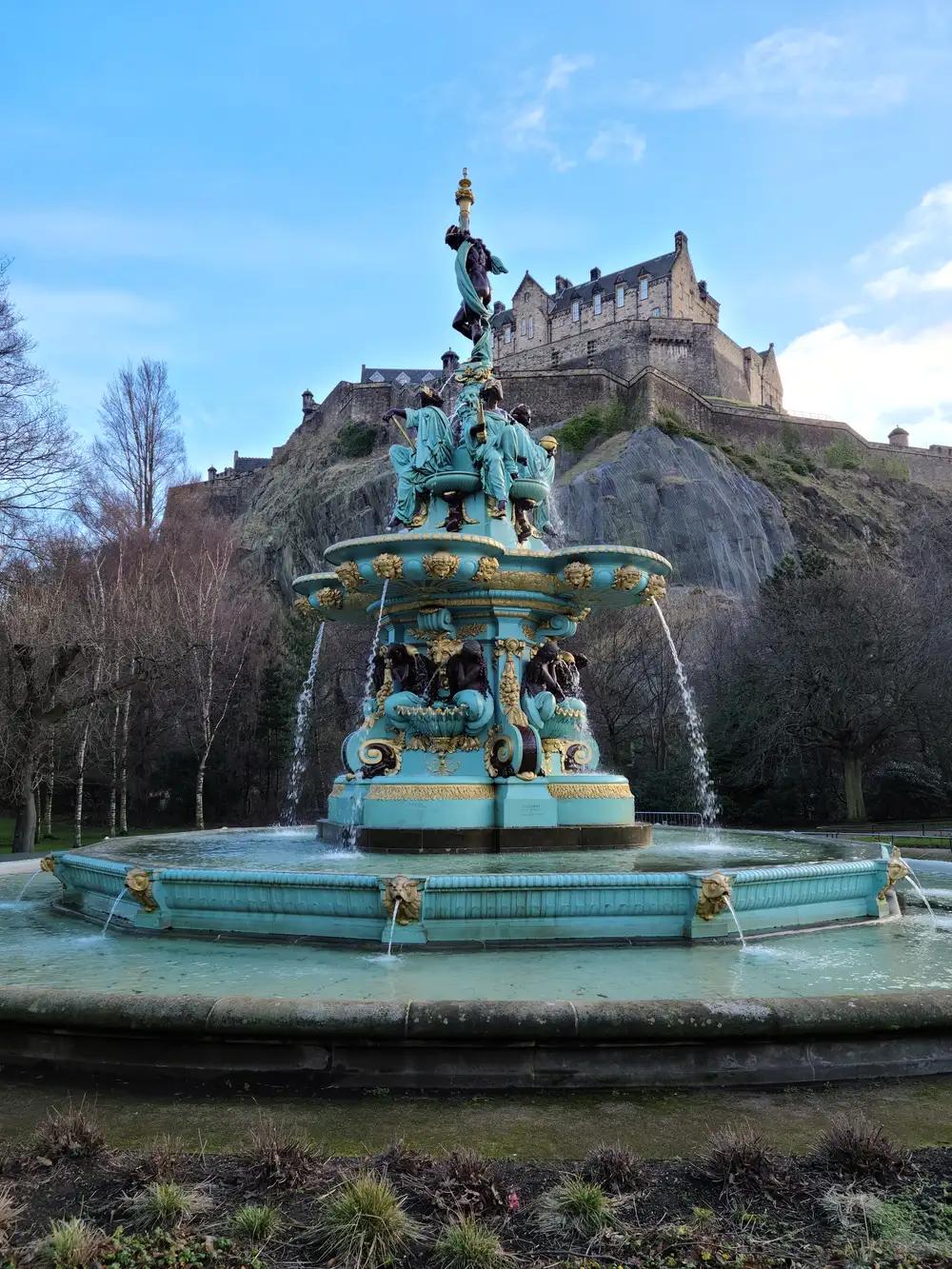 Restored turquoise and gold Ross Fountain in West Princes Street Gardens with Edinburgh Castle on its crag behind