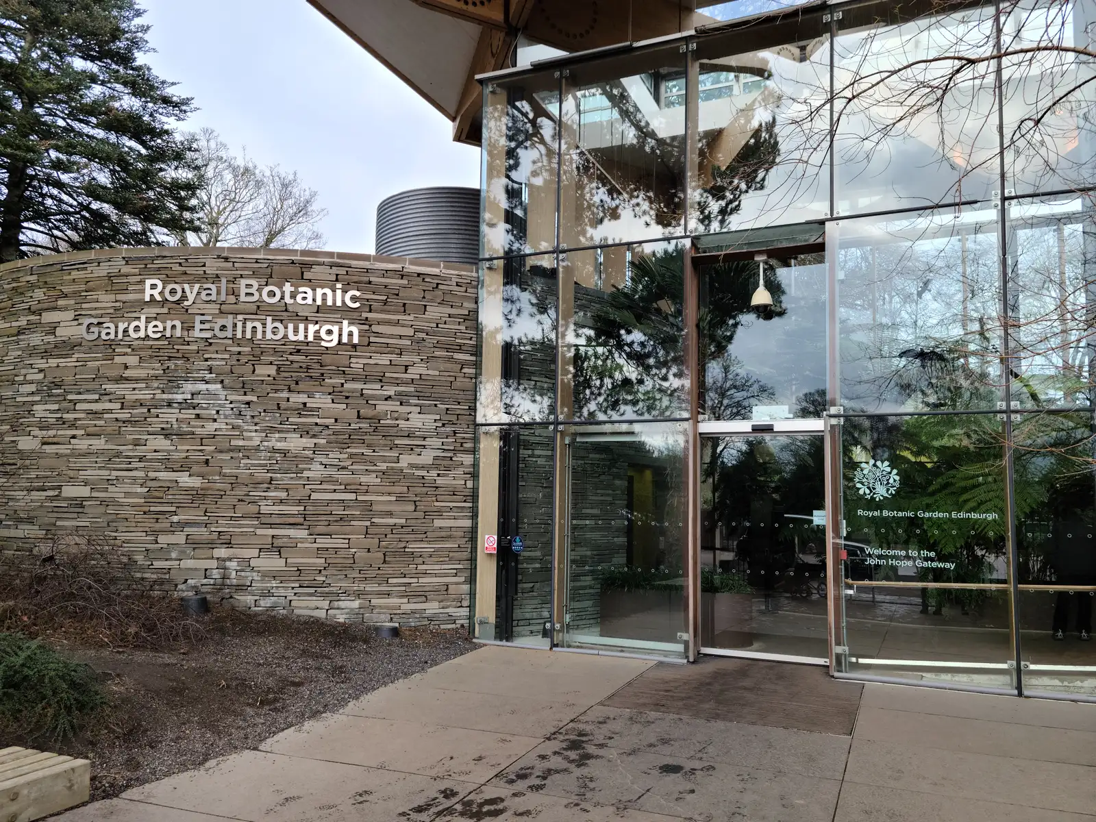 Curved drystone wall signage and glass John Hope Gateway entrance to the Royal Botanic Garden Edinburgh in winter