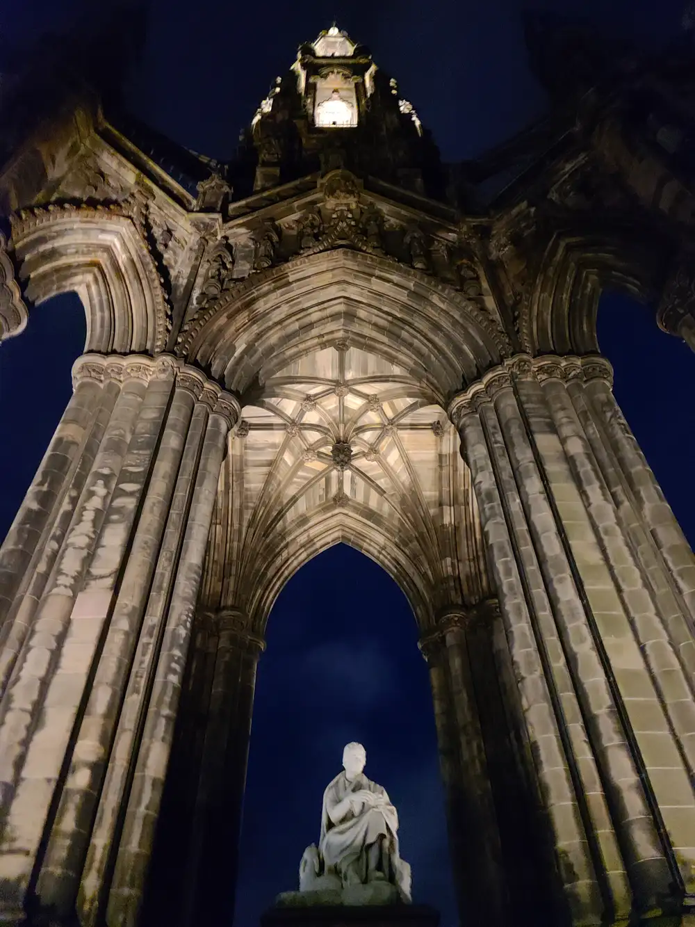 Floodlit Scott Monument at night in Edinburgh with carved gothic arches above the white marble Sir Walter Scott statue