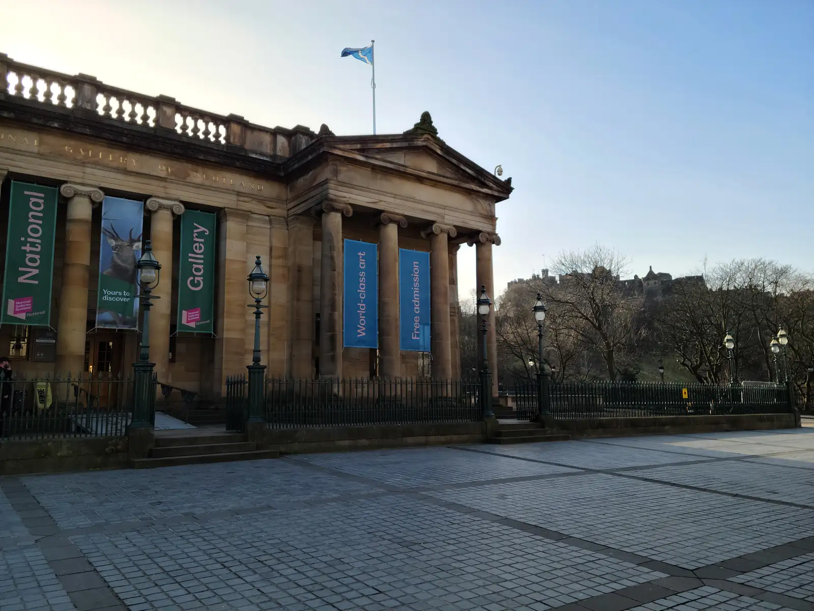 Scottish National Gallery's columned portico on The Mound in Edinburgh with Saltire flag flying and Castle Rock to the right