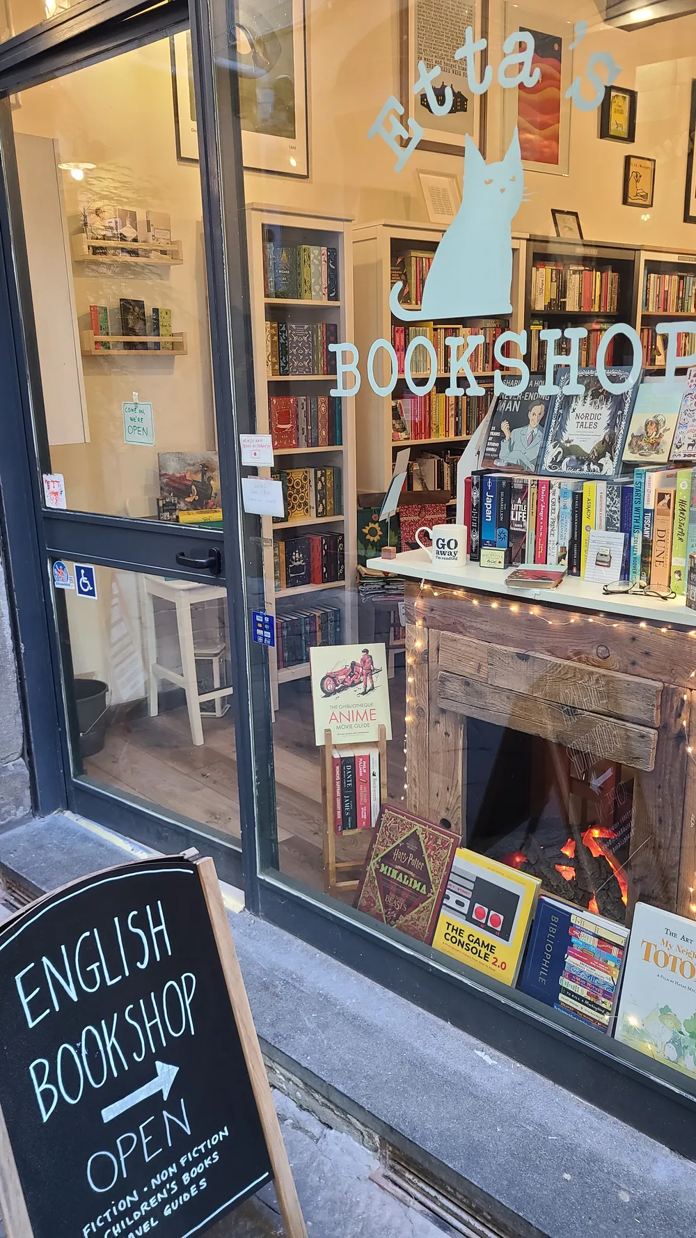 English Bookshop storefront on Via Fillungo in Lucca with a chalk sign reading English Bookshop Open and colorful books displayed in a warmly lit window