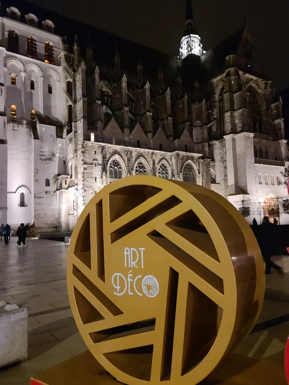Art Deco sign near the Basilique de Saint-Quentin glowing against the night sky