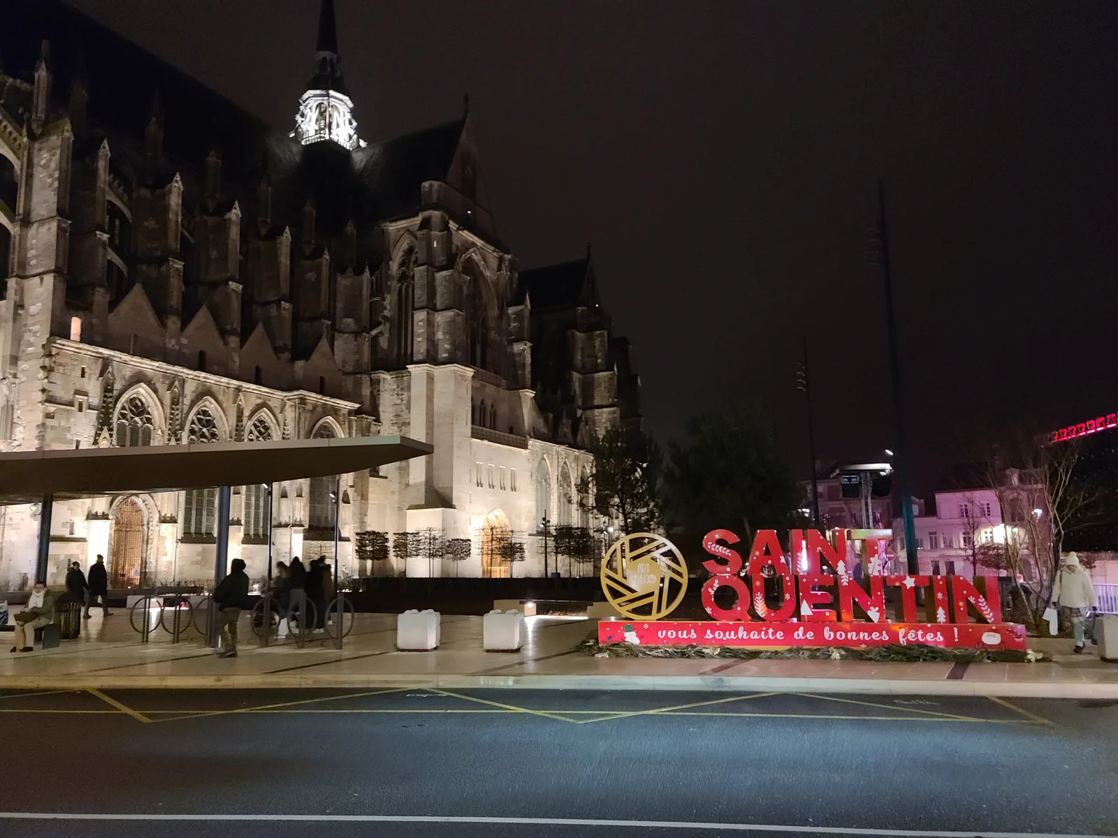 Basilique de Saint-Quentin illuminated at night with a Christmas sign in the foreground