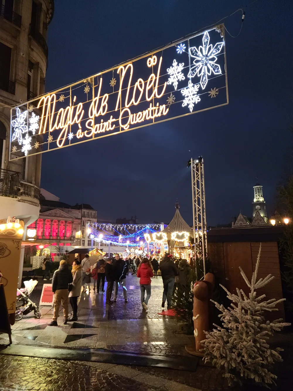 Saint-Quentin's Magie de Noël Christmas market at night, festive lights reflecting off wet streets