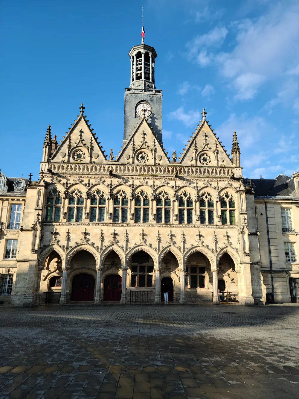 Gothic clock tower of the Hôtel de Ville rising above Saint-Quentin's main square
