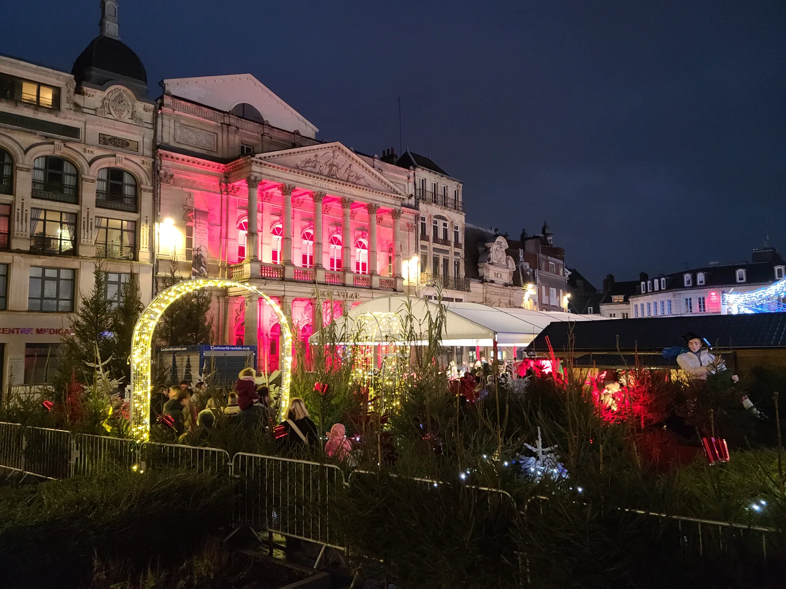 Théâtre Jean-Vilar lit with pink Christmas market lights in Saint-Quentin at night